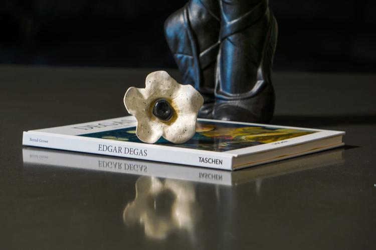 Handmade ceramic flower on a stack of art books